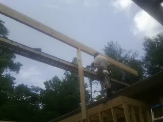Carpenter setting a ridge beam over a new addition frame — Ice Dam Removal by Roofing Brothers in Roaring Gap