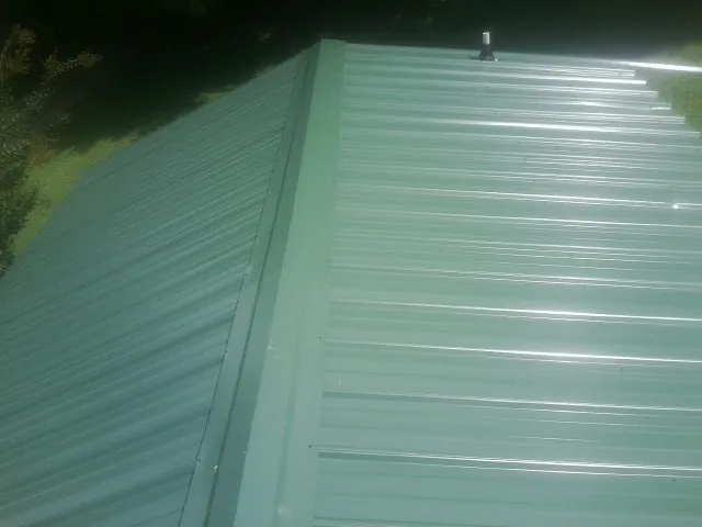 New green metal panels meeting at the ridge of a roof — Flat Roof Repair work by our crew in Roaring Gap