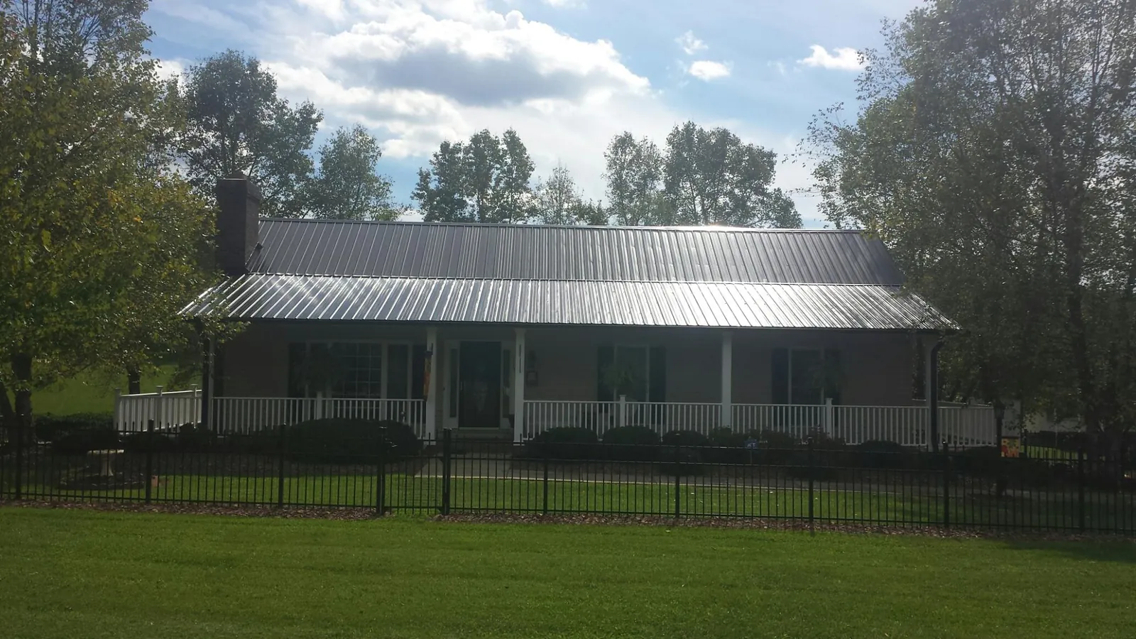 Gray metal roof on a brick ranch with a full width front porch — Gutter Guard Installation work by our crew in Roaring Gap